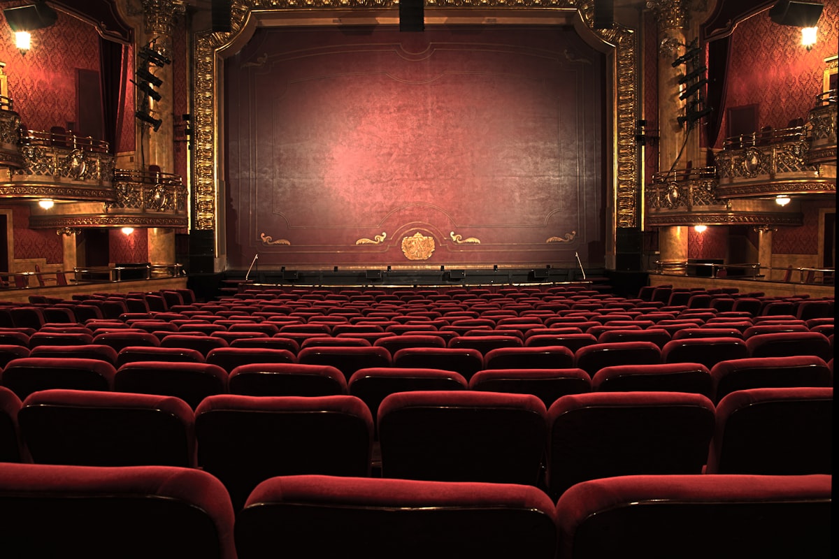 Festlicher Theatersaal mit roten Sitzreihen und beleuchteter Bühne.