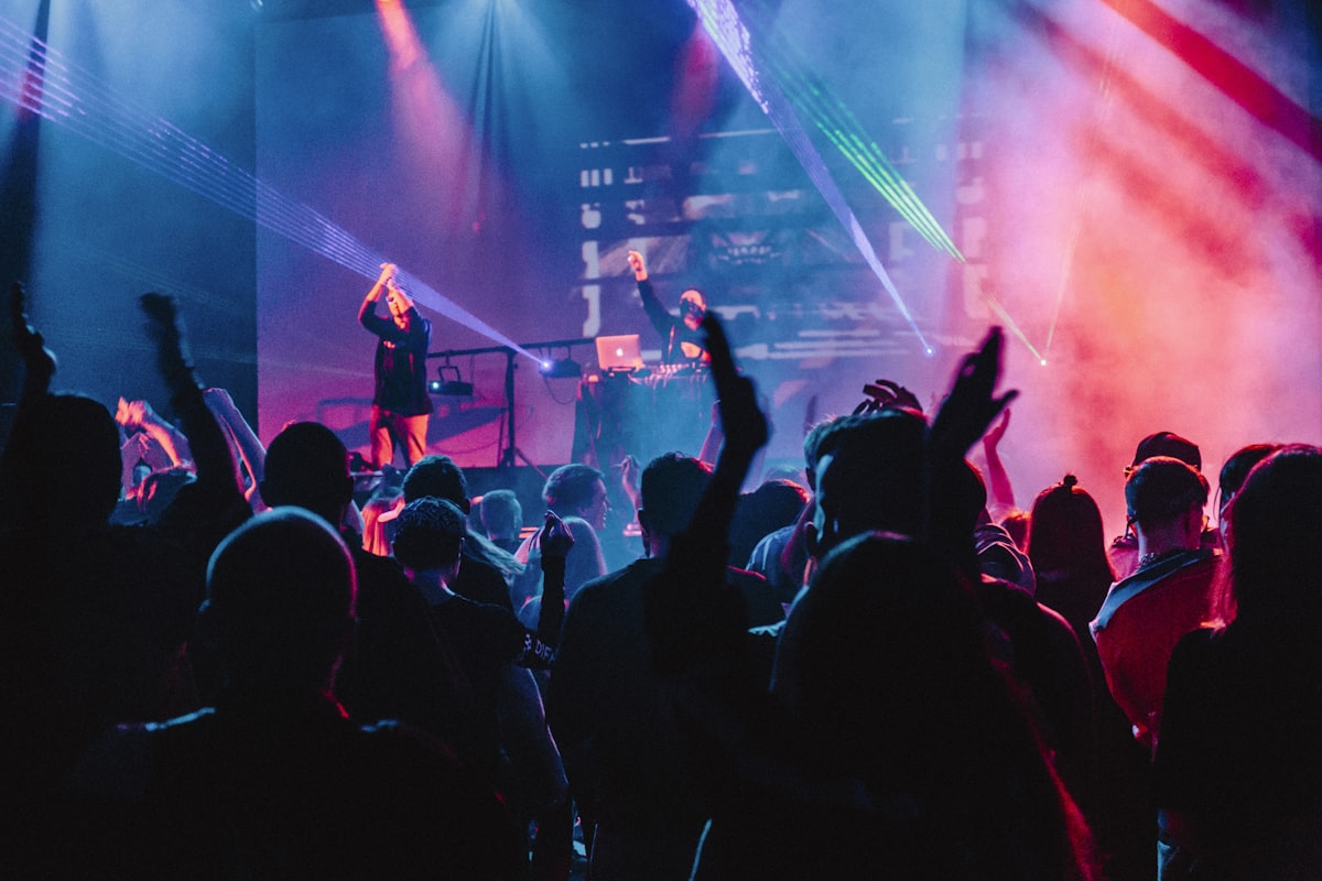 Publikum vor einer Bühne mit Live-Musikern und farbigem Licht.